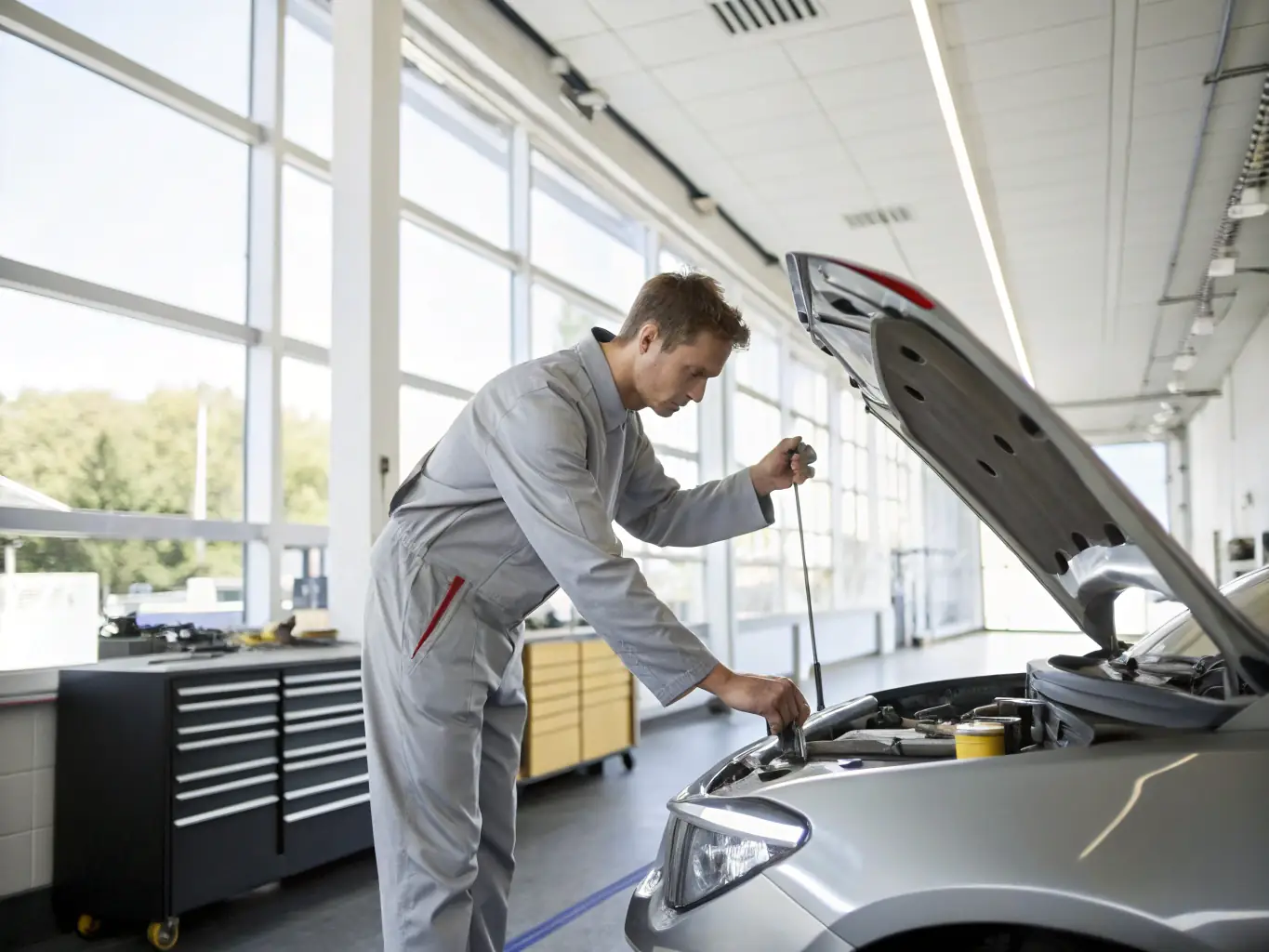 A mechanic performing an oil change on a car, with the Qadora logo subtly visible in the background, emphasizing the quality and care provided during the service.
